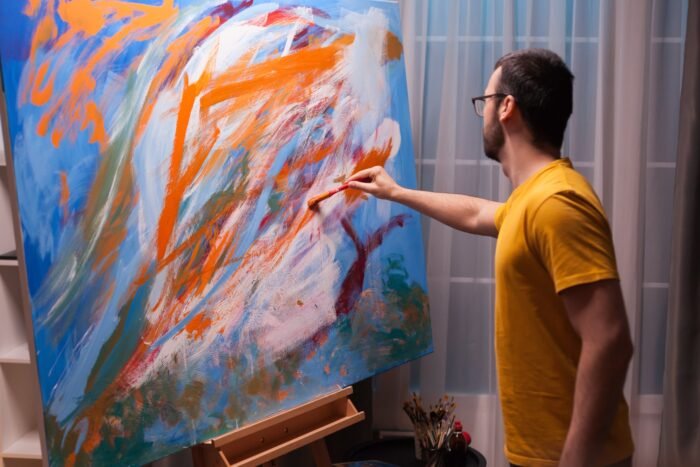Homme peignant sur une toile pour créer son propre tableau déco