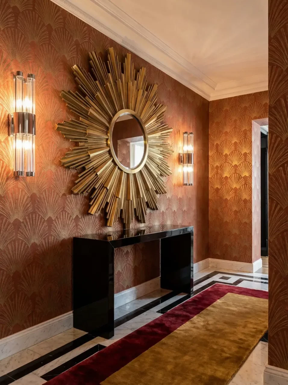 entree neo art deco miroir soleil console doree Entrée d'appartement neo art déco avec grand miroir soleil doré, console noire laquée, papier peint éventail terracotta et or