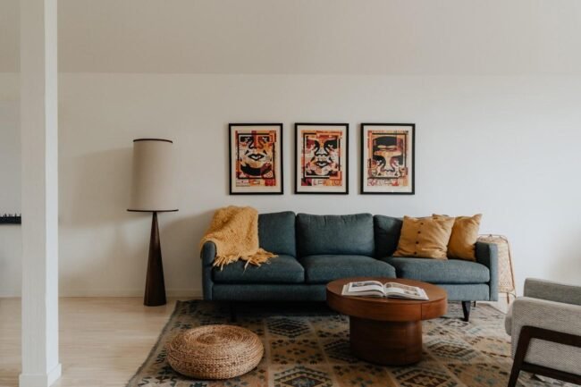 Salon contemporain avec canapé bleu et trois cadres alignés au mur au-dessus du canapé